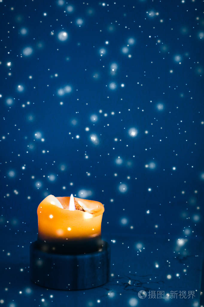 黄色节日蜡烛在蓝色闪闪发光的雪地背景上鲁迅