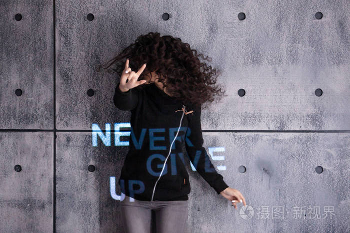 振作起来欢快的年轻卷发女子在水泥墙上跳舞多色投影说永不放弃