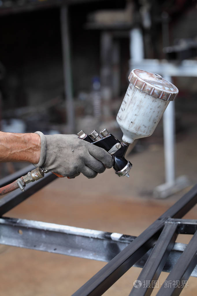 用油漆枪油漆金属的工人