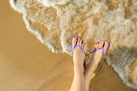 在海边沙滩上用人字拖的女人的特写镜头,文字空间.海滩配件照片