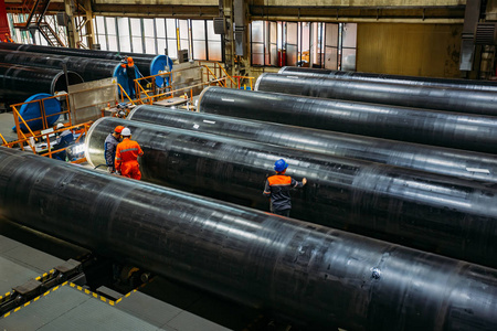 工人们在工厂检查新的涂层管道照片