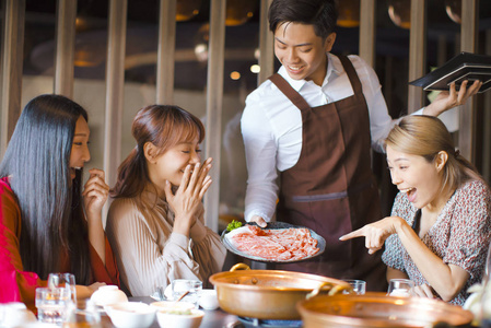快乐的侍者端上牛肉片和上菜的朋友们照片