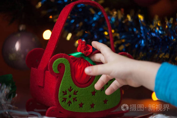 孩子们的手在绿树下伸手去拿新年礼物。新年和圣诞节快乐。