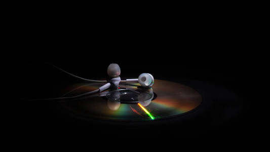 cd光盘和白色耳机,背景为深色.概念:听音乐照片