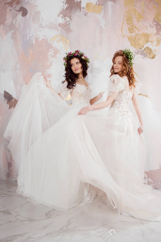 两个迷人的新娘头上戴着美丽的春天花环穿着婚纱的漂亮年轻女子
