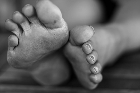 桌子上是一个脚趾甲涂了漆的女人的脏脚照片