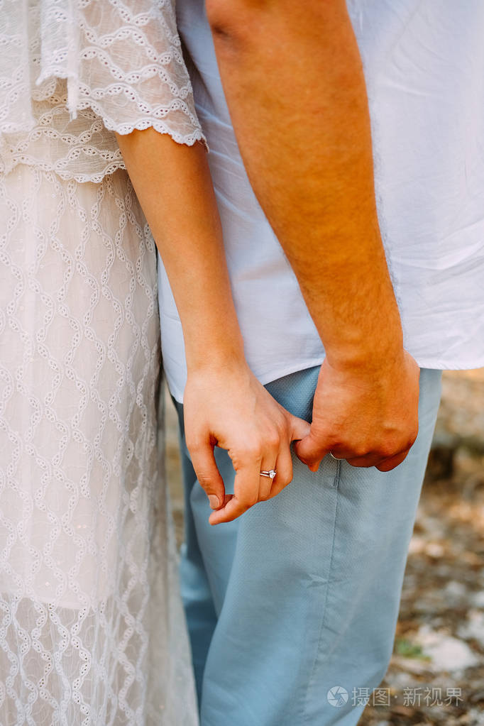 一对情侣手牵着手戴着结婚戒指