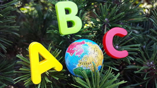 英文字母表的第一个字母和小玩具地球仪位于云杉的树枝上照片