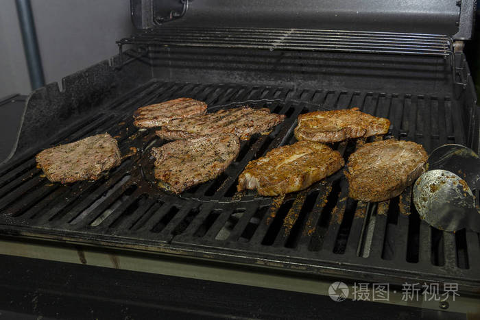 多汁的大块肉在烤肉架上煮。腌好的肉在铁炉上炸。