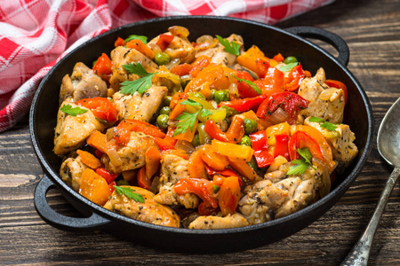 木桌上蔬菜炒鸡肉.照片