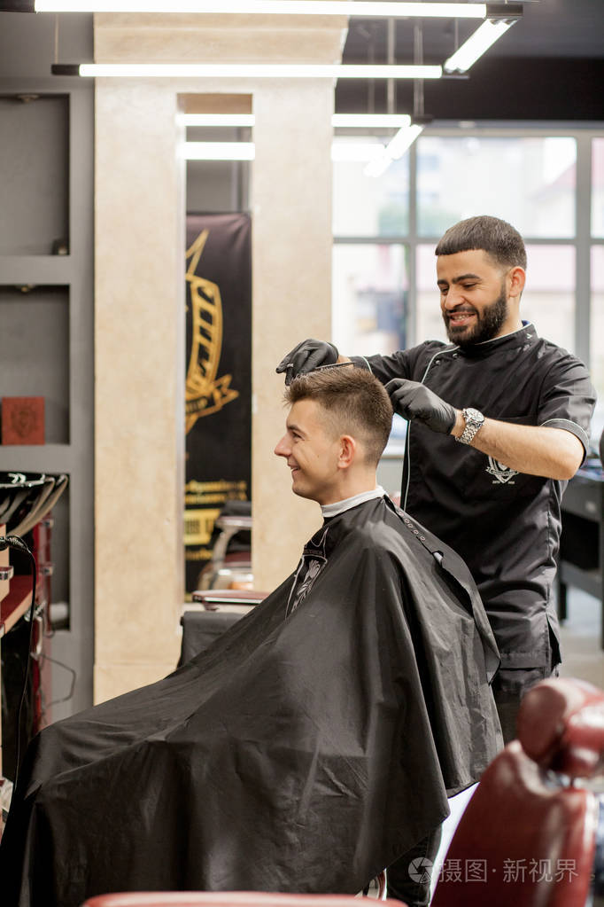 现代理发店的野蛮人理发师使发型成为男人美发师用理发器做发型概念