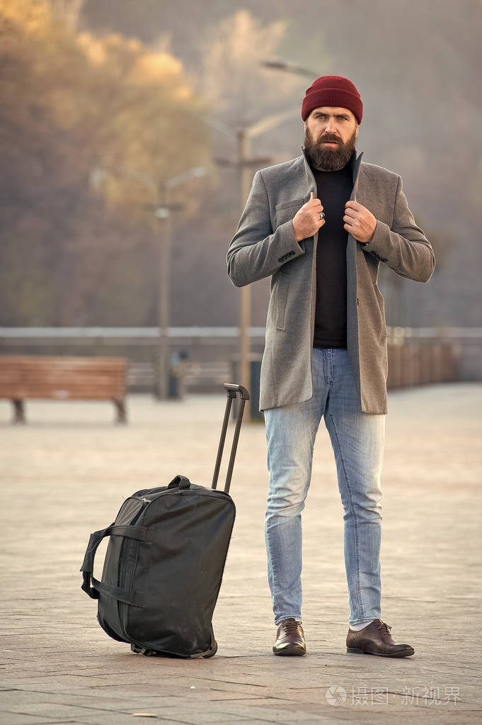 一个留着胡子的时髦男人带着大行李袋等出租车把他带到酒店旅行小贴士