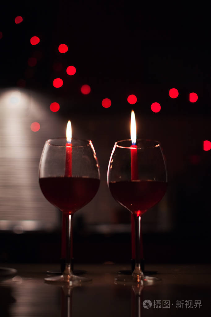 浪漫晚餐两杯酒和烛台在黑暗中背景是新年灯光