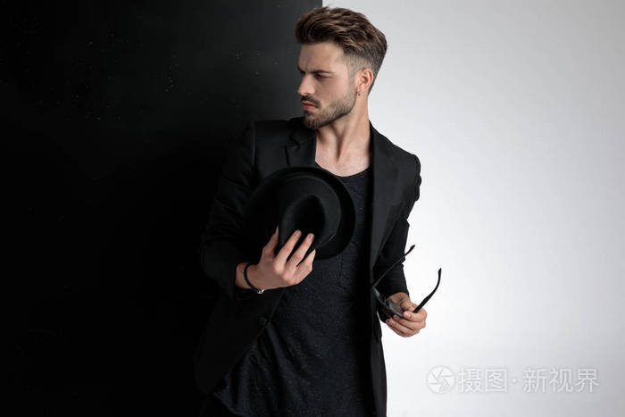 傲慢的年轻人拿着帽子和墨镜