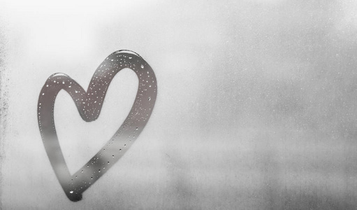 在玻璃上画的心灰色的心画在出汗的玻璃上,上面有许多水滴,在潮湿的