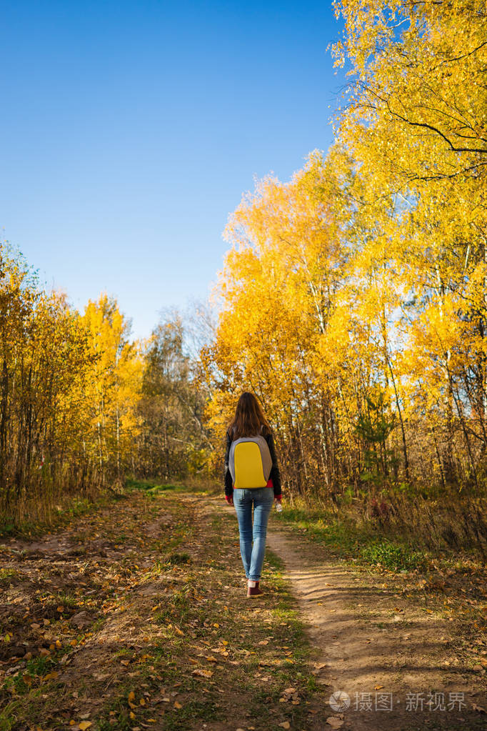 一个背着背包的年轻女子独自在秋天散步