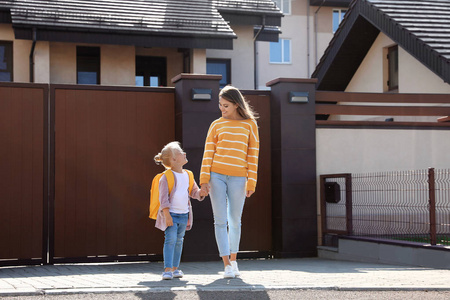 年轻的母亲带着她的孩子在街上上学照片