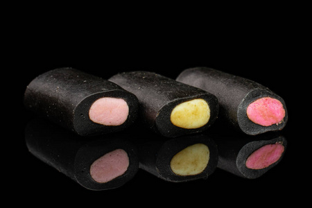 黑色玻璃上隔离的黑色甘草糖白底黑甘草糖