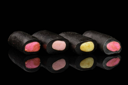 黑色玻璃上隔离的黑色甘草糖照片