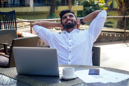 岸边阿拉伯一个英俊成功的印度男人,穿着时髦的自由职业者,手里拿着一