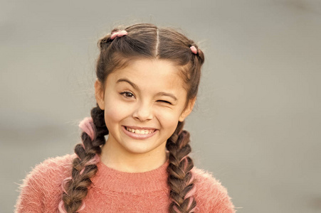 女孩眨眼开朗的脸灰色背景.女孩开朗,对一切都满意.