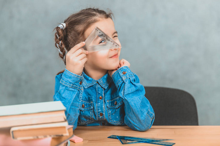 有趣的小女孩好奇的玩在学习过程中,通过三角形看.照片