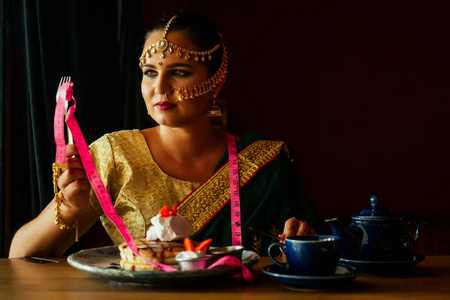 阿拉伯松饼特写画像绝望的女人穿着绿色纱丽和黄金珠宝商看着煎饼与生