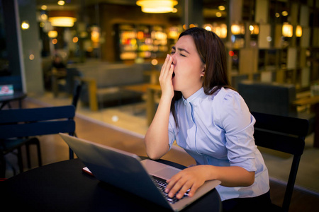 晚上在咖啡馆用笔记本电脑的女人她困了照片