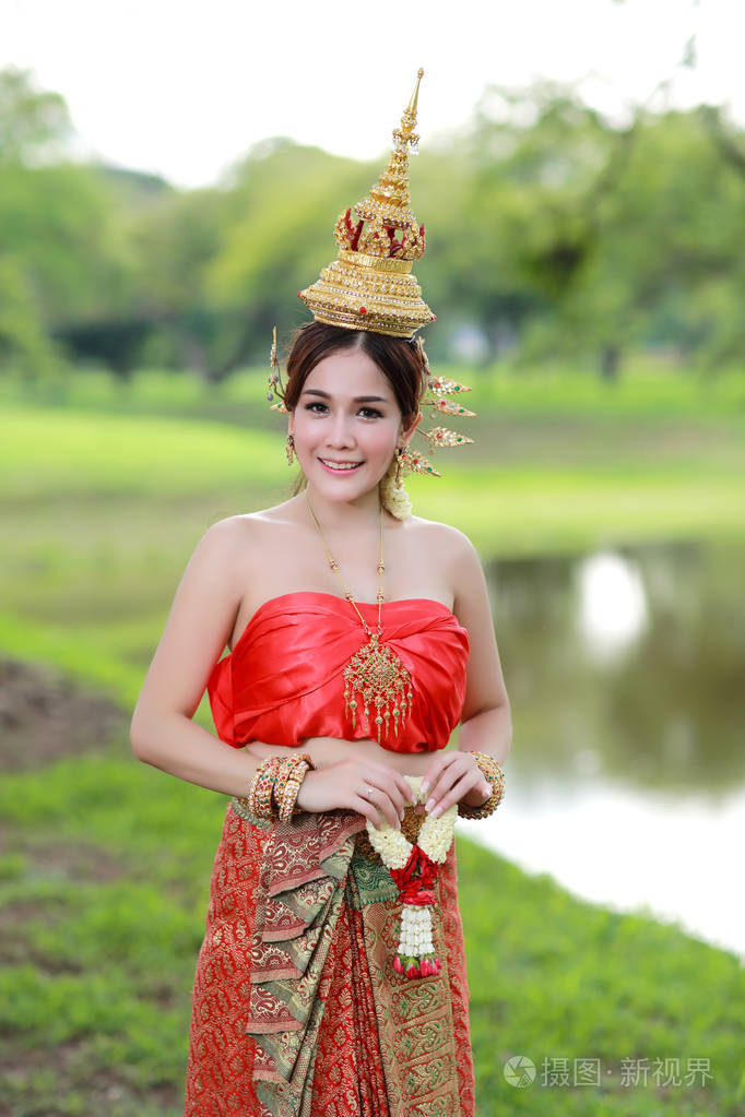 时尚亚洲女孩在古庙里穿着泰国传统服装手里拿着方向盘花