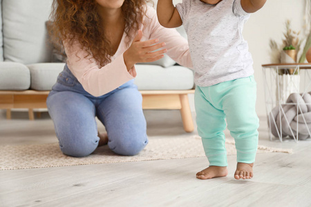 的小宝宝在卧室里和妈妈一起学走路孩子学走路学着和妈妈一起走路的