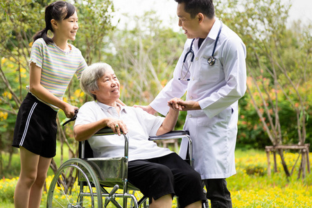 友好的亚洲男性医生问候康复,鼓励,安慰老年女性患者,医生用听诊器牵