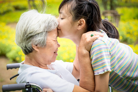 外国老奶奶特写,快乐的亚洲老年妇女与美丽的小女孩拥抱,亲吻,微笑在