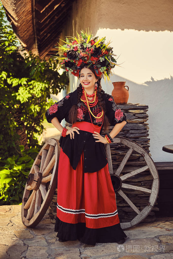 黑发女孩穿着黑色和红色刺绣的乌克兰正宗民族服装,戴着花环,站在一间