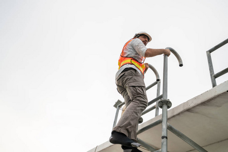 爬网站的年轻的工人或工程师爬梯子.照片