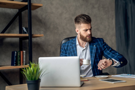 留着胡子的经济学家穿着正装,在智能手表上检查时间,以便按时完成工作