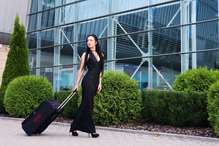微笑着的女乘客拉着行李箱穿过机场大厅,走向出口照片