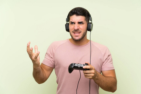 年轻帅哥在孤零零的绿墙上玩游戏机控制器照片