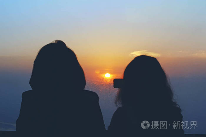 两个女人在观察塔上看日出的剪影