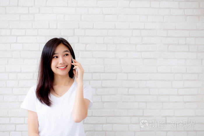 美丽的人像年轻的亚洲女人说话智能手机和smi
