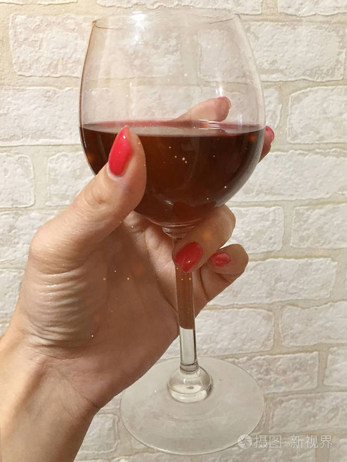 图为双手拿着一杯酒