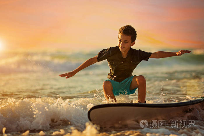 无忧无虑的男孩在五彩缤纷的夕阳下冲浪
