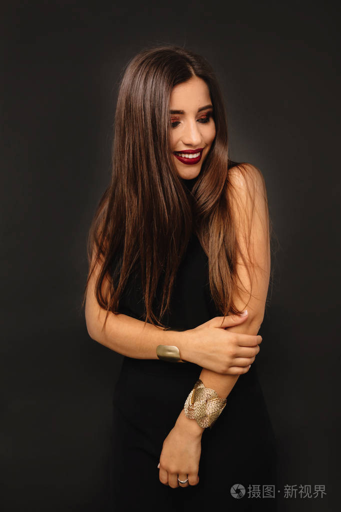 黑色背景下一头黑色长发和节日化妆的迷人微笑女孩的肖像