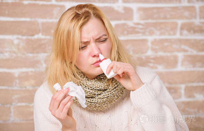 鼻涕的漂亮女孩拿着滴鼻液一位病妇注射滴鼻液可爱的女人护理鼻部感冒