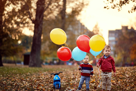 孩子们的兄弟们一起在秋天的公园里玩气球照片