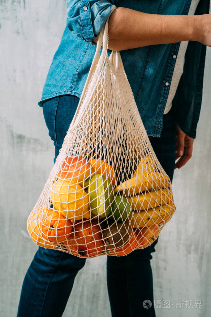 特写镜头一个年轻女子拿着一个有机新鲜水果在可重复使用的购物袋串