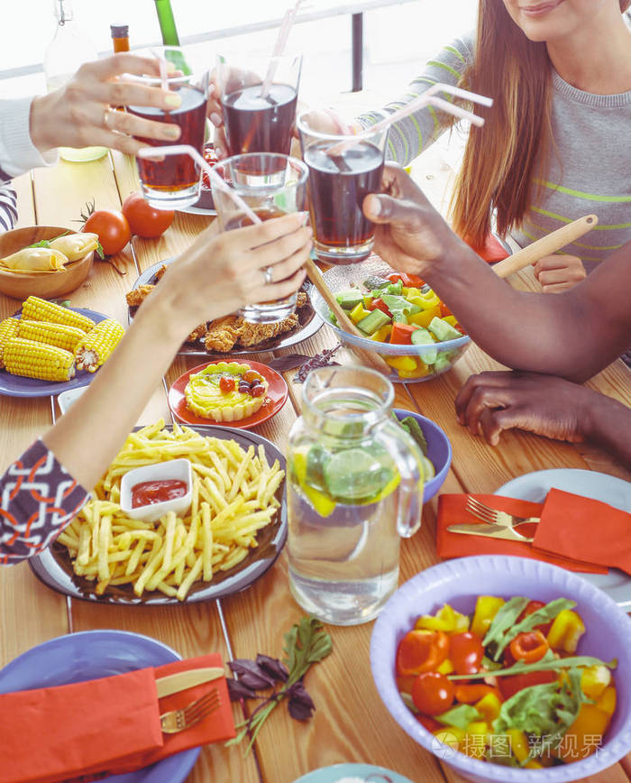 坐在木桌旁吃饭的人群的俯视图餐桌上的食物人们吃快餐