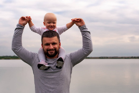 抱在男人怀里的孩子.在水边走走.孩子和爸爸在天空的衬托下.照片