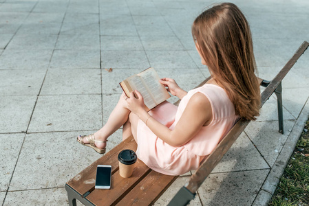手机小说女生夏天在城里看书,秋春坐在长凳上,粉红色的衣服,一杯咖啡