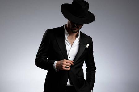 神秘的年轻优雅男子,穿着燕尾服,戴着黑帽子照片