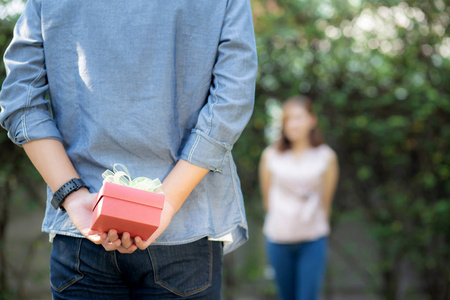 年轻亚洲男子背着礼盒惊喜女友图片